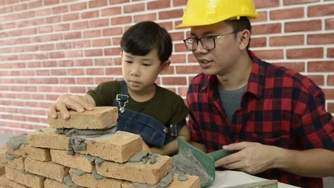 Father teaching his son to use a spirit level and doing masonry. Vidéo 115522869