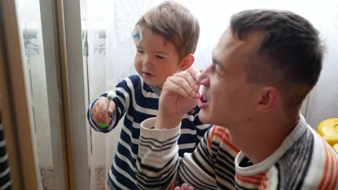 Father teaching little kid teeth brushing. Dad and his little son at morning. Stock Footage 153397380