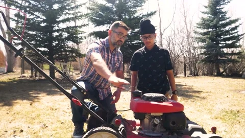 Father teaching son functions of lawnmower in backyard Video stock 221041569