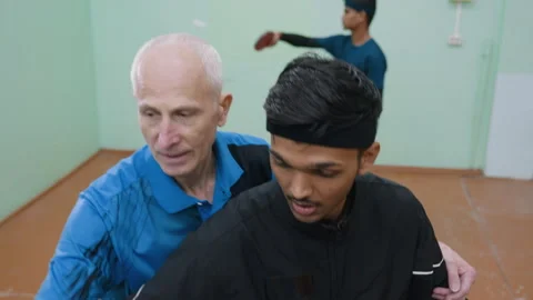 Father Teaching Son Good Posture During Tennis Serve as Another Player Trains Stock Footage 319205684