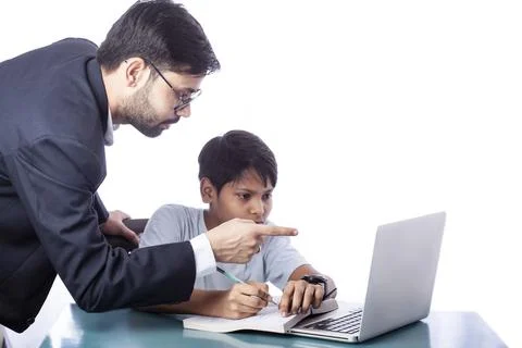 Father teaching son with the help of computer and books, pointing finger towards Foto stock