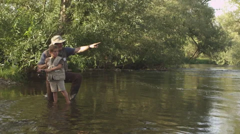 Father and son fishing together at river, Stock Video