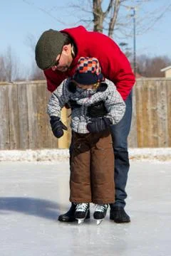Father teaching son how to ice skate Stock Photos