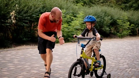 Father teaching son to ride a bike. Man and kid learning to ride bicycle. Stock Footage