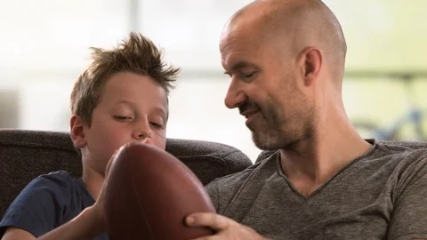 Father telling his son about football on the couch Video stock 78874997