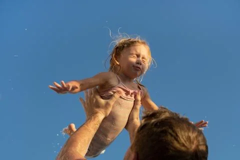 Father throwing up two year old caucasian blonde girl,playing.Dad and daughter Stock Photos