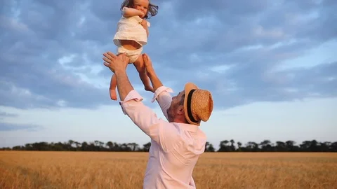 Father throws up gently cute toddler throws up cute toddler in wheat field Stock Footage 120413809