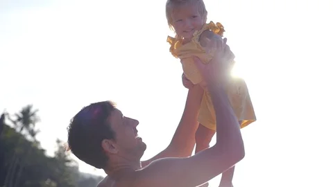 The father throws his daughter up, in the rays of the sun in the summer. slow Stock Footage 90047975