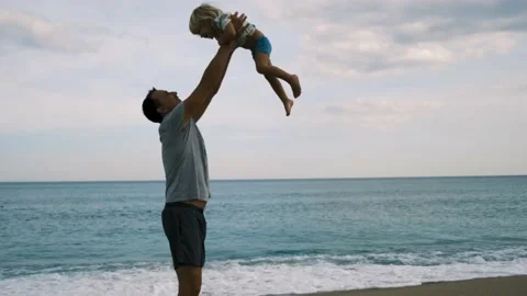 Father throws his son in the air on the beach slow motion Stock-Footage 220732043