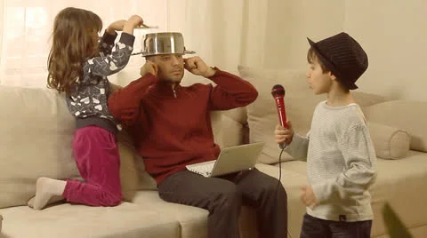 Father is trying to work on lap top, while his children are having fun. Stock Footage 22907817