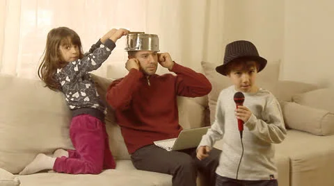 Father is trying to work on lap top, while his children are having fun. Stock Footage 22911710