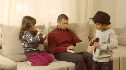 Father is trying to work on lap top, while his children are having fun. Stock Footage 22915909
