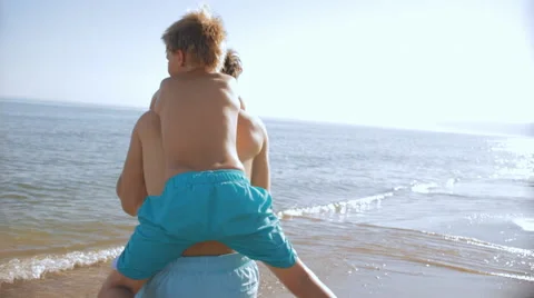 Father twirling with son on back on beach Stock Footage 43620398