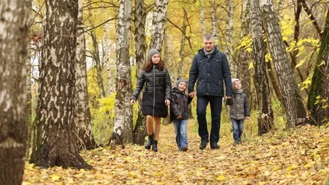 Father with two sons and one daughter walks in autumn forest, slow motion Video stock 276360473
