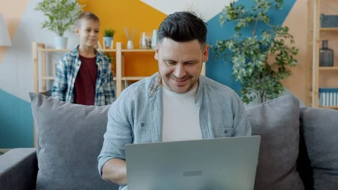 Father using laptop then talking to son adorable kid pointing at computer screen Stock Footage 127959857