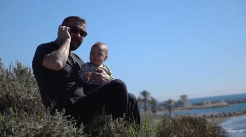 Father using mobile and holding son, super slow motion   Stock Footage 60064872