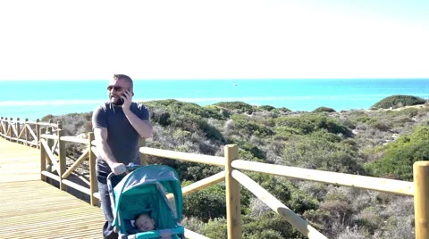 Father using mobile and walking with baby in stoller, super slow motion Stock Footage 60064678