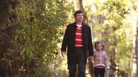 Father walks down autumn path with daughter Stock Footage 80126814