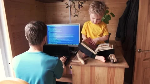 Father work at home office, small child sits near and read book Видео 130494746
