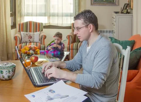 Father working in home office and son playing Stock Photos