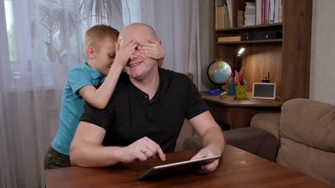 A father working at home with a tablet, a boy hugging his father at home. Stock Footage 305293629