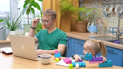 Father works remotely in the kitchen on a laptop, daughter little child pla.. Stock Footage 321116074