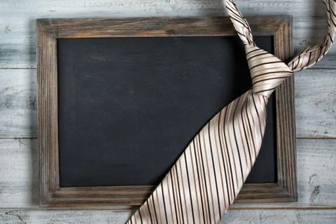 Fathers day concept, empty framed chalkboard and tie on wooden background Stock-Fotos