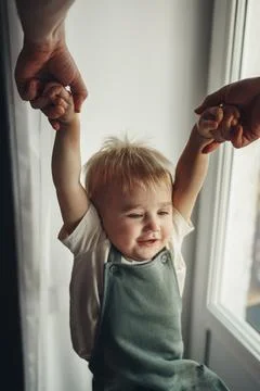 Fathers hands pull happy son up by hands at home. Top wiev Foto stock