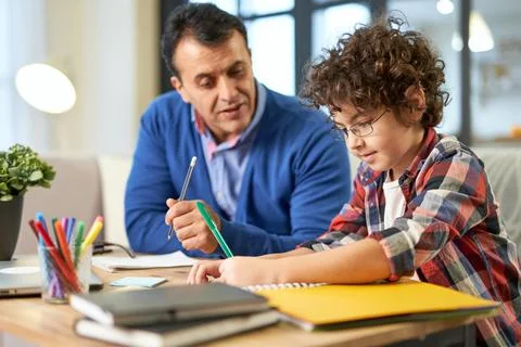 Father's help. Caring middle aged latin father helping, discussing homework with Stock Photos