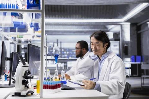Fatigued laboratory engineer stretching while using PC for DNA data analysis Stock Photos