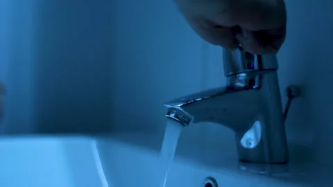 Faucet being turned on and hands being washed in blue bathroom Stock Footage 199433194