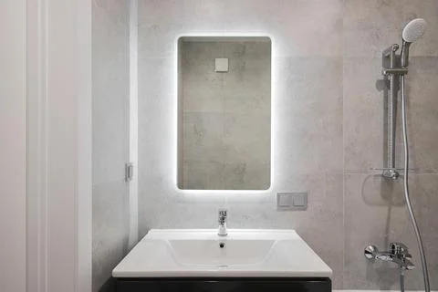 Faucet with ceramic sink and mirror in the bathroom Stock Photos