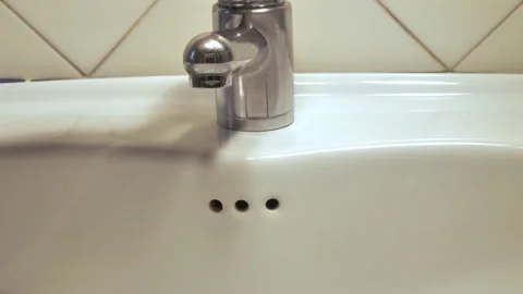 The faucet is opened, water flows into the drain basin, then was closed. Pouring Stock Footage 147653701