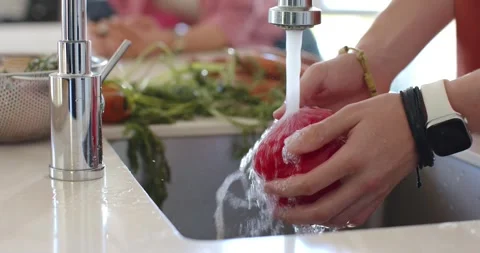 Faucet running as hands rinsing and rotating red pepper in sink toward cutting Stock Footage 344645097