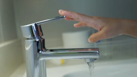 Faucet with water flowing and child hand turn off Stock Footage