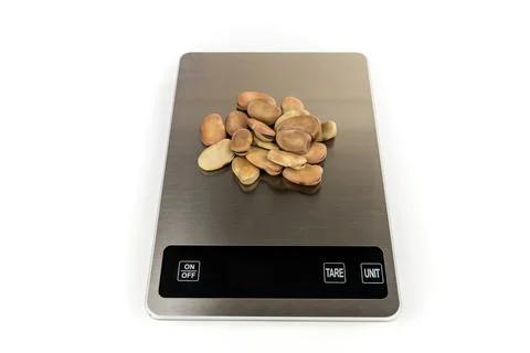 Fava beans on a silver scale isolated over white top down view Stock Photos