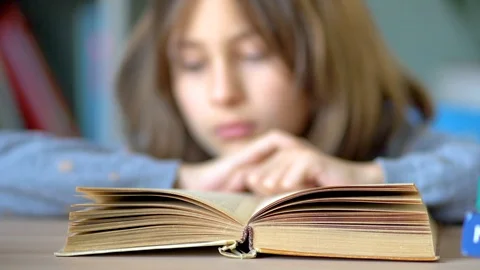 Favorite hobby is reading. On the table is an open book. A young schoolgirl Stock Footage 127337146