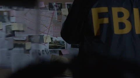 FBI agent looking at evidence board from behind Stock Footage 312455446