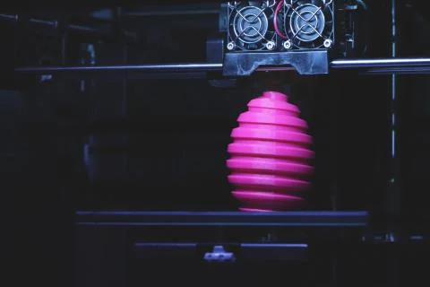 FDM 3D-printer manufacturing wound pink easter egg sculpture - front view on  Stock Photos