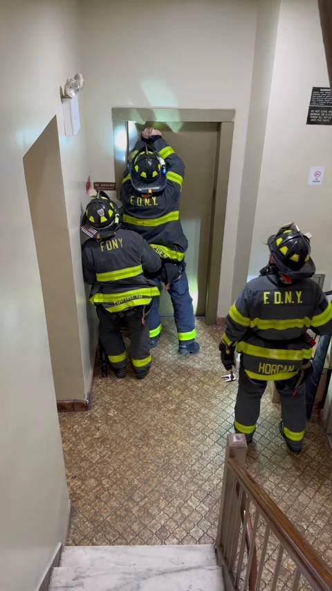 FDNY firefighters use a Halligan bar to force open stalled elevator doors in NYC Stockbeeldmateriaal 344589286