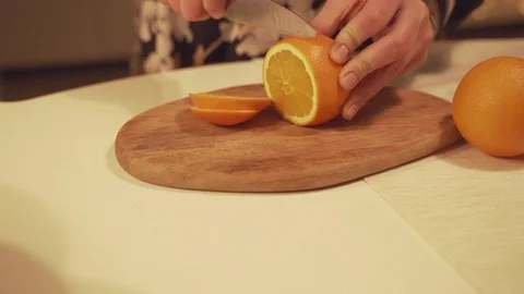 Feamale hands cutting orange on cutting board for homemade mulled wine with Stock Footage 100976460