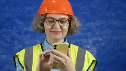 Feamle Engineer in the construction helmet and yellow vest with mobile phone  Stock Footage 166857582