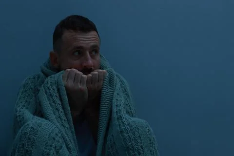 Fear of darkness. Scared man with blanket on light grey background, space f.. Stockfoto's