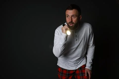 Fear of darkness. Scared man with flashlight on black background, space for.. Stock Photos