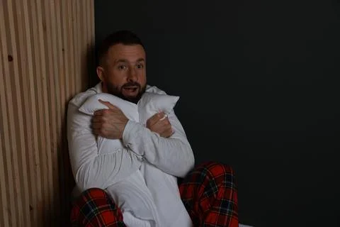 Fear of darkness. Scared man hugging pillow indoors at night Stockfoto's