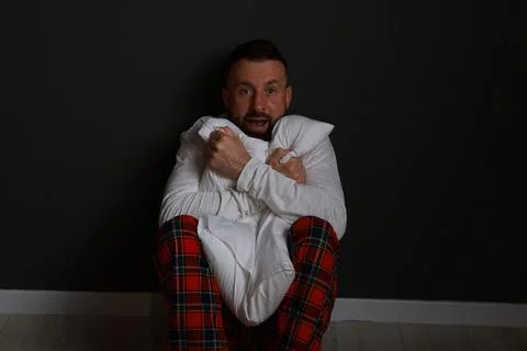Fear of darkness. Scared man hugging pillow indoors at night Stock Photos