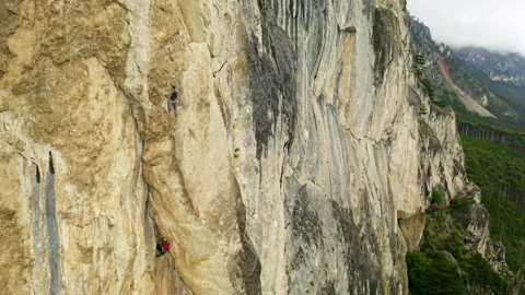 The Fearless Ascent: A Thrilling Image of a Man Climbing a Towering Cliff Stock Footage 257221603