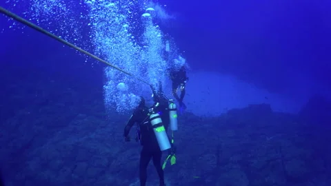 Fearless divers descend by cable to bottom of ocean. Stock Footage 232765984