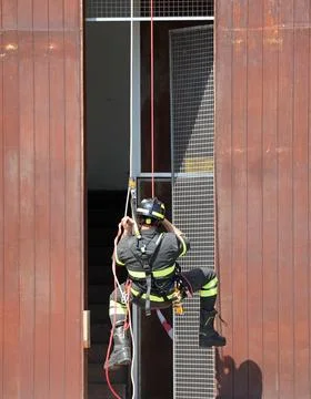 Fearless firefighter rappelling from building using ropes carabiners and pr.. Fotos de archivo