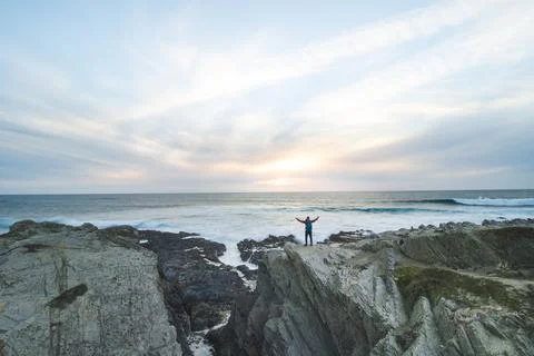 Fearless man with a backpack watching the sunset over the Atlantic Ocean in P Stock Photos